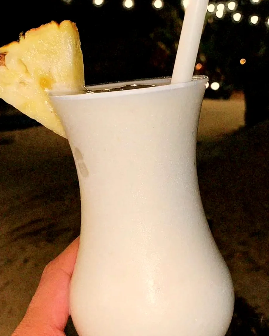 Drink na mão com as luzinhas e a areia da Praia do Preá ao fundo