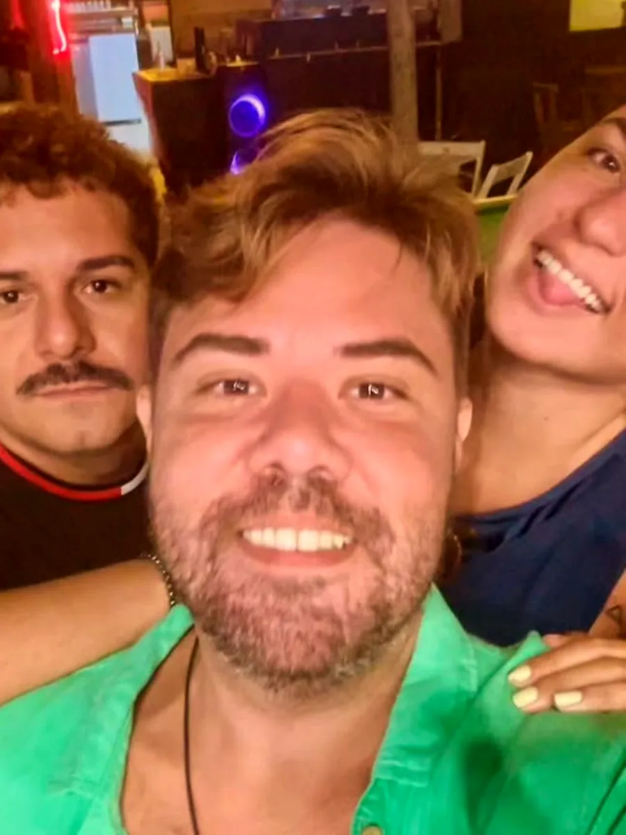 Três amigos abraçados na frente do balcão do bar